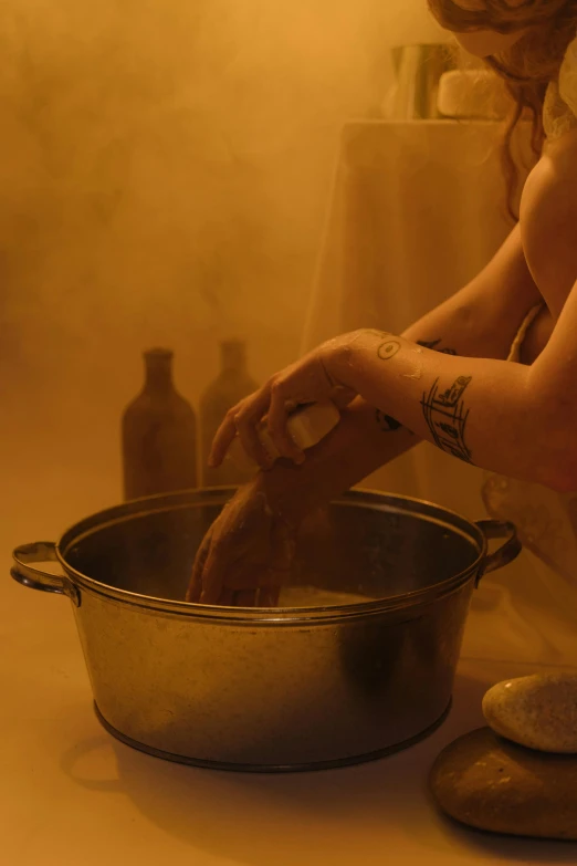 the woman's arm is touching a silver bowl with a liquid