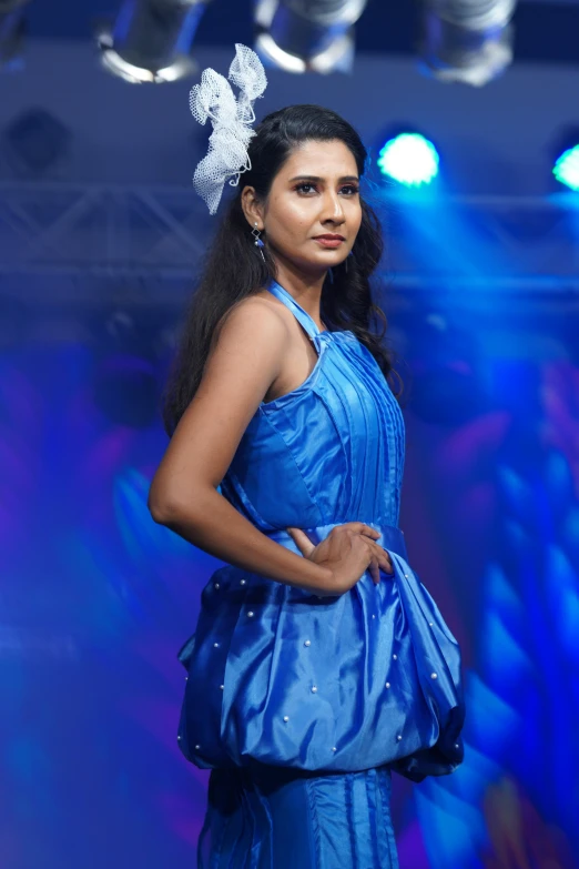 a woman dressed in a blue gown on a runway