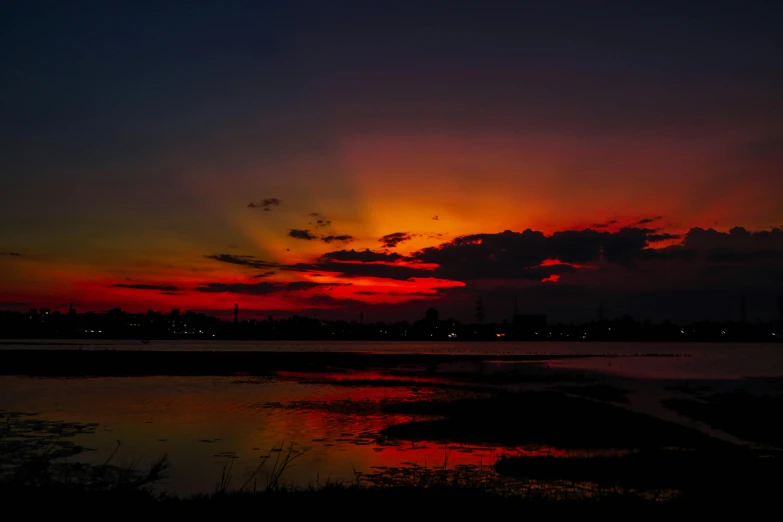 the setting sun in a cloudy sky over a water body