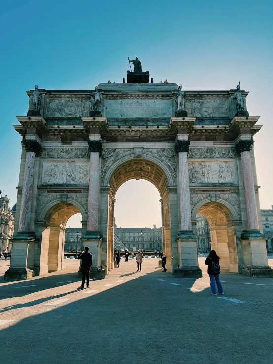 people walking by an archway in a plaza