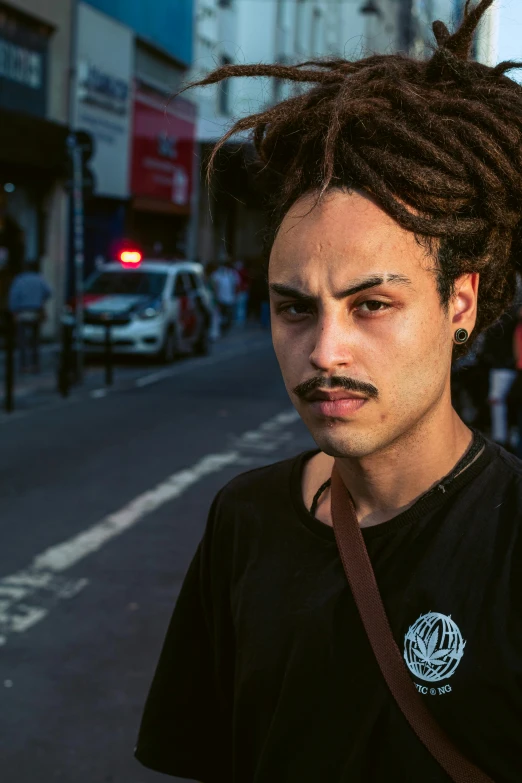 a man is wearing a black t shirt with dreads on his head