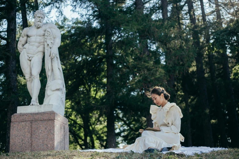 a person sitting on a ledge in front of a statue