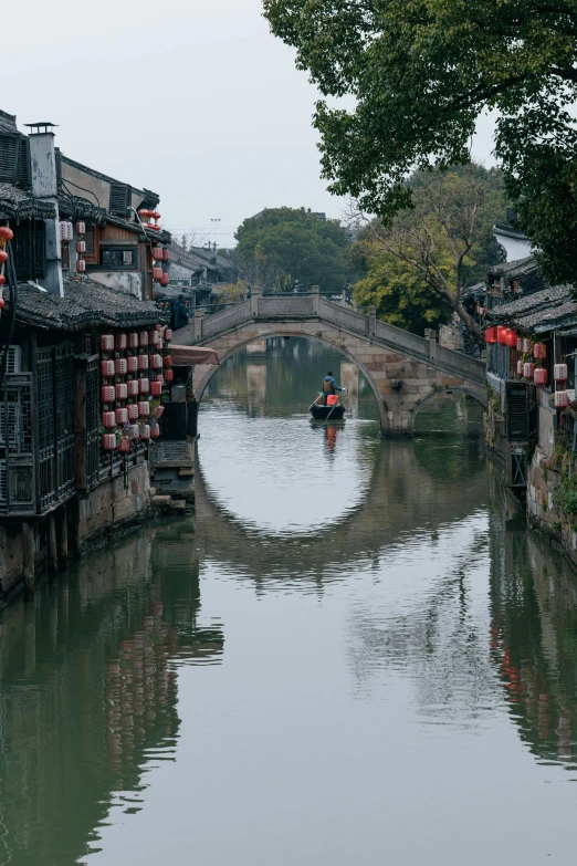 small boat traveling down the canal near old chinese buildings