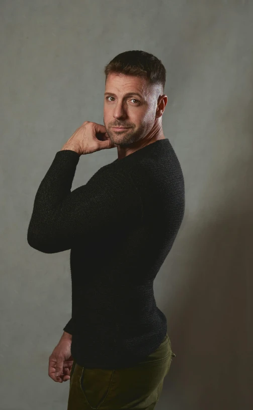 a man poses while wearing black sweater