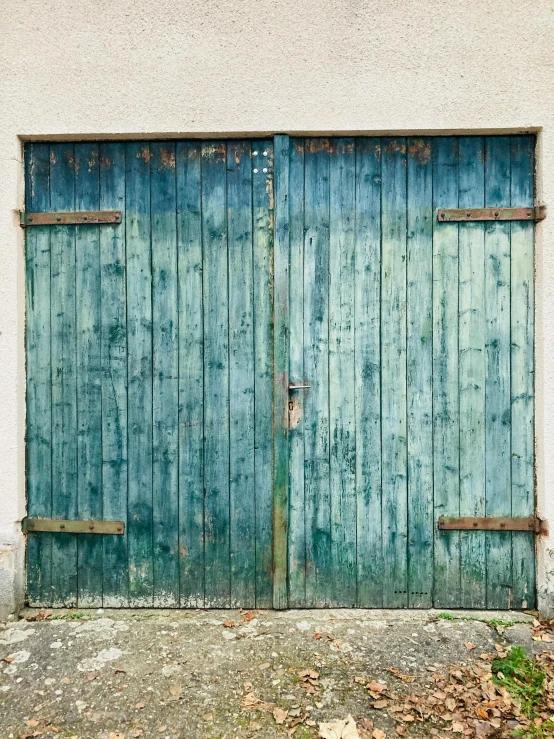 an old door is closed to two weathered wooden doors