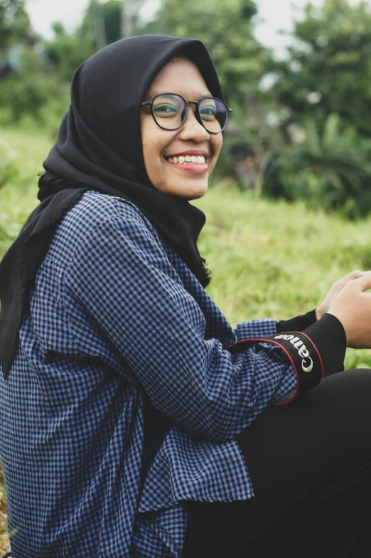 a woman sitting in a field of grass and looking at her phone