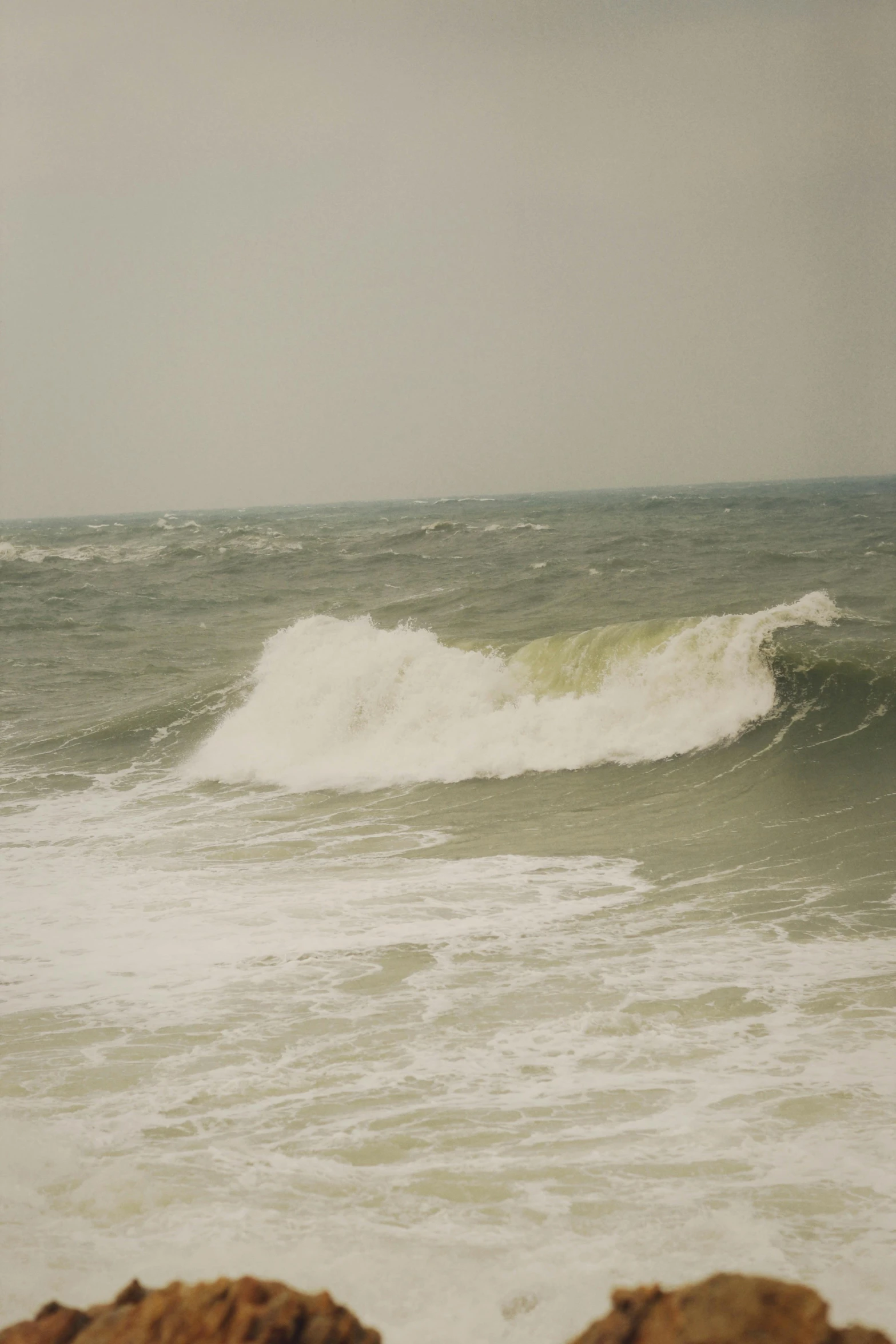 a large wave crashes on the shore while people watch