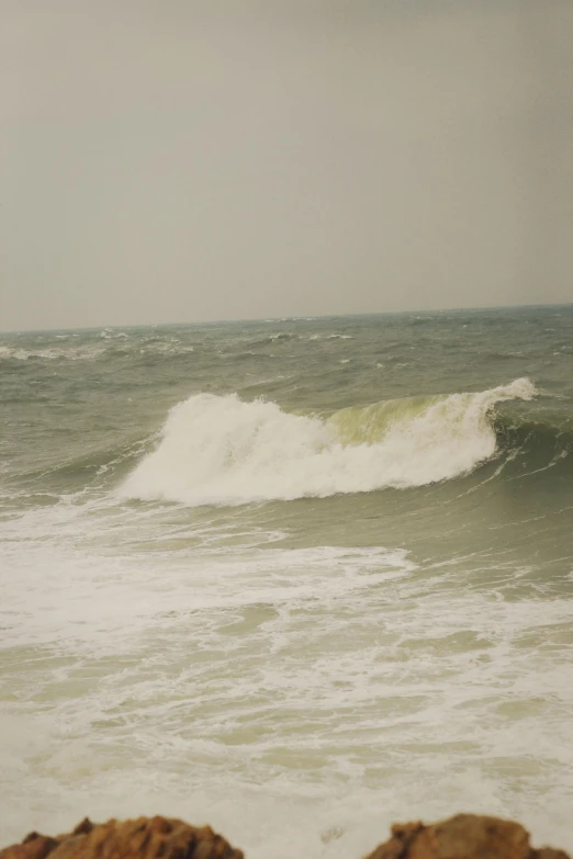 a large wave crashes on the shore while people watch