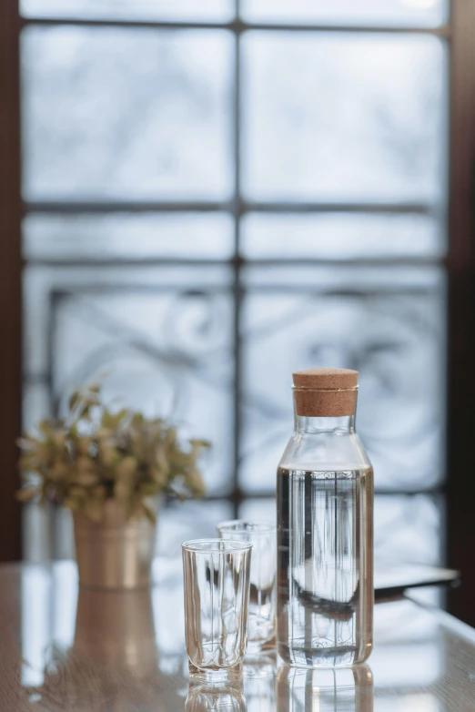 two glasses are sitting next to a bottle on the table