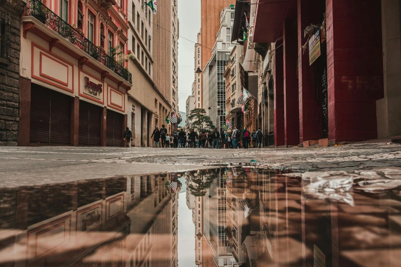a street lined with tall buildings has a reflection in it