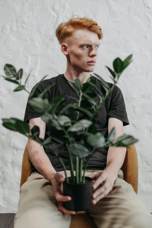 a man sitting on a chair holding a potted plant