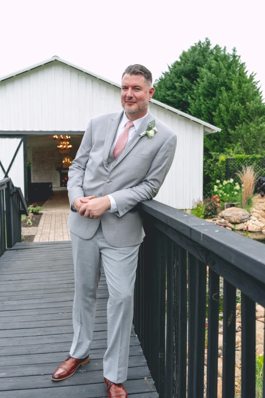 a well dressed groom leans on a rail