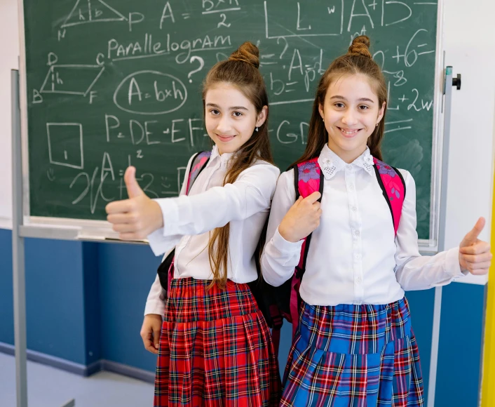 two girls are standing with their thumbs up and posing for the camera