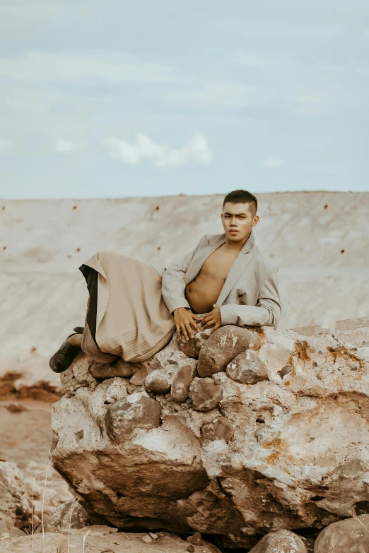 the man is sitting on a rock and looking up