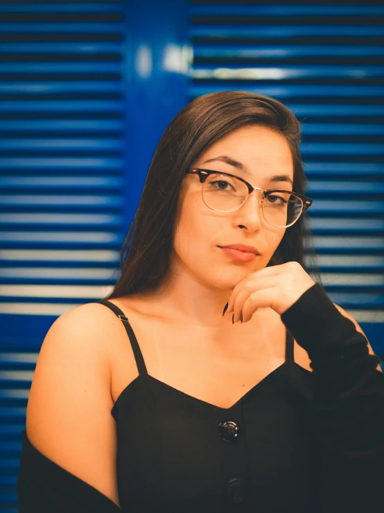 a woman wearing glasses sitting down looking at the camera