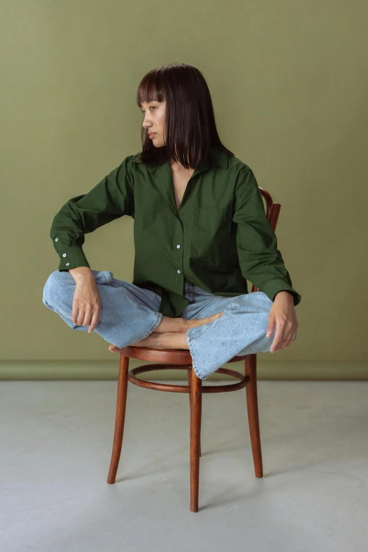 a young man sits in a chair and is adjusting his jeans