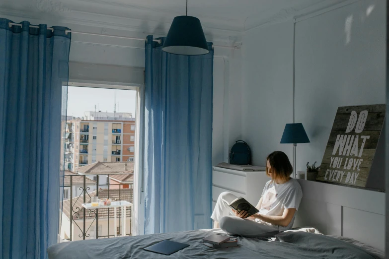 a girl reads while sitting on a bed