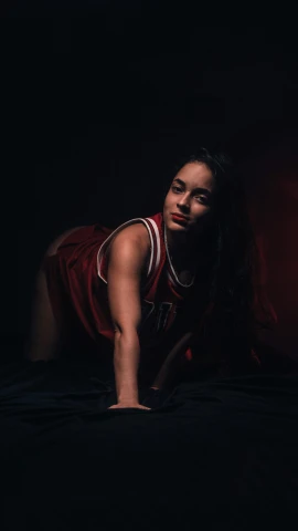 a woman in red basketball uniform laying on a bed