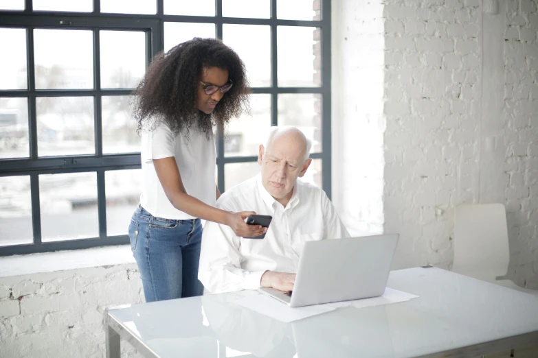 an elderly man is using a laptop computer as a woman looks at the screen