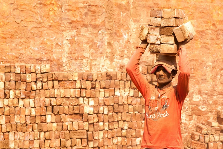 a man carrying some bricks over his head