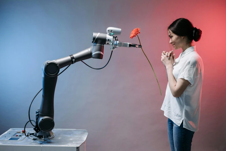 a woman holding a flower standing next to a machine