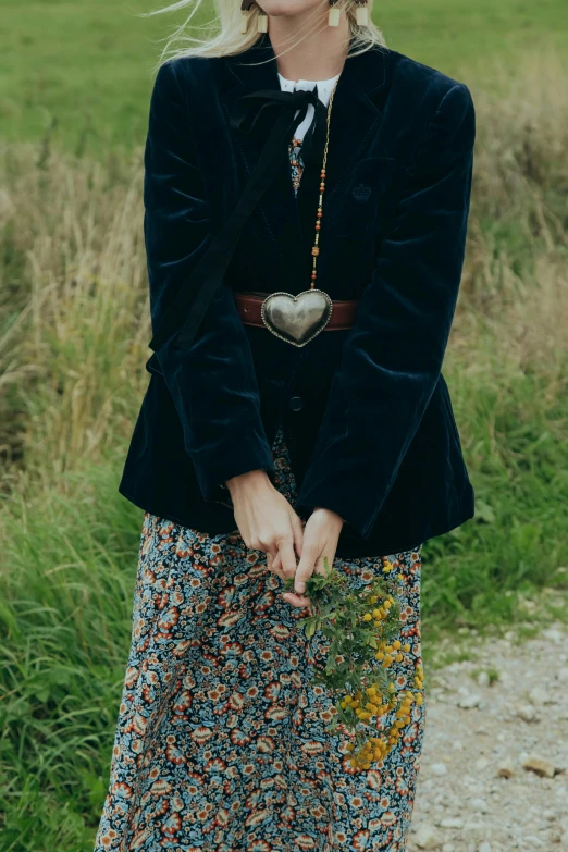 a blond woman in glasses holding flowers and standing