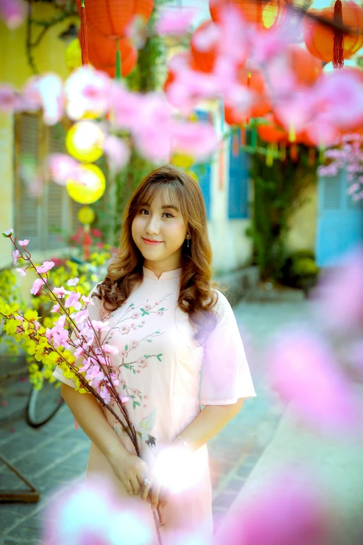 a girl holding pink flowers standing in front of some pretty pink flowers