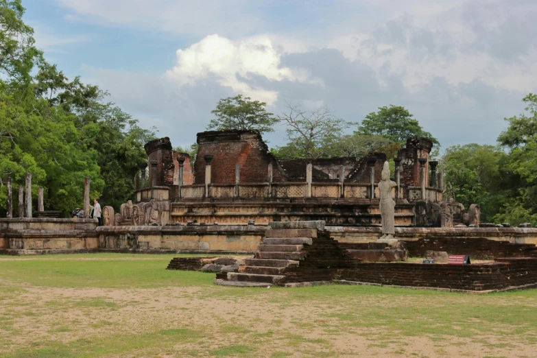 two people standing in the grass near some ruins