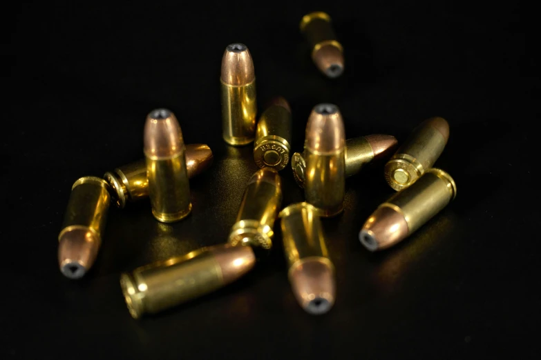 several bullet casings and rounds on a black surface