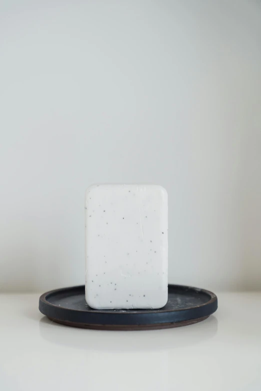 a block of soap sitting on a black and round dish