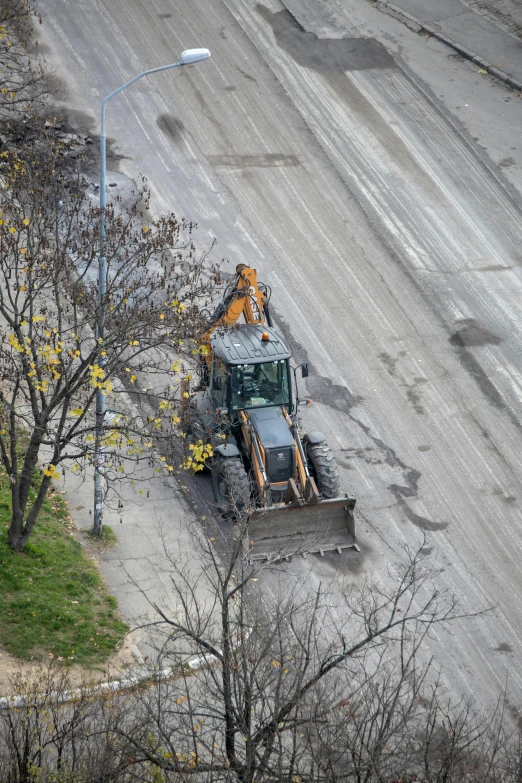 a tractor driving down a street next to a tree