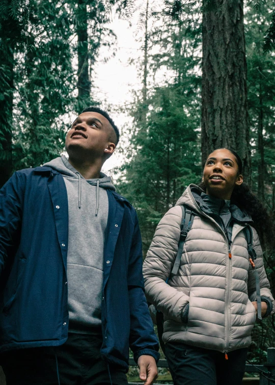 a couple of people standing in a forest with trees