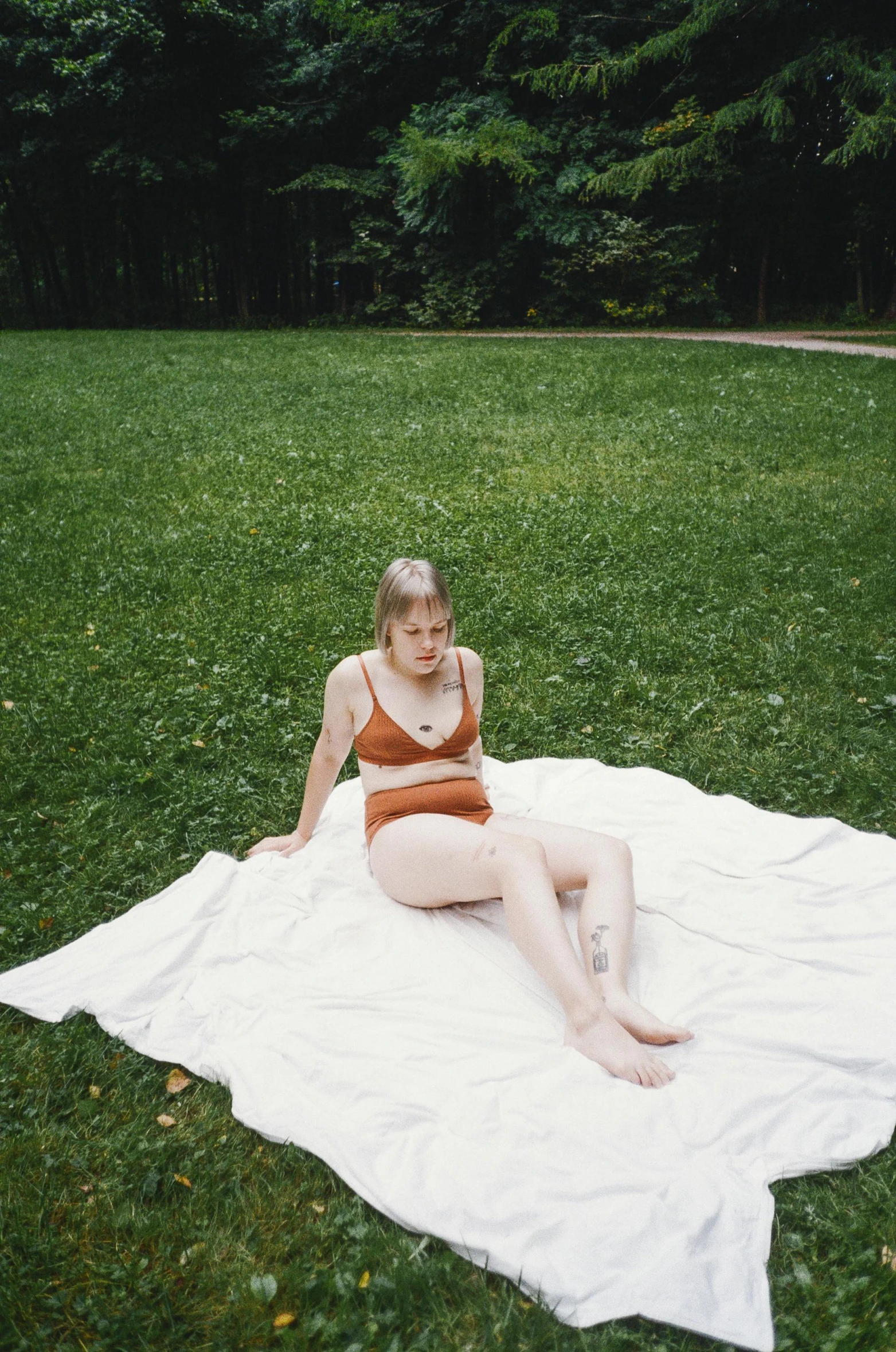 a woman sitting on a towel in the grass