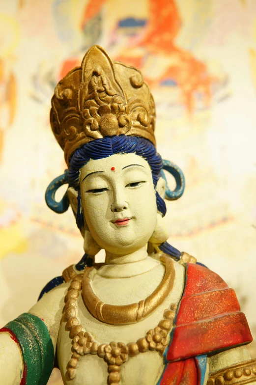 a statue is wearing a golden crown and blue beads