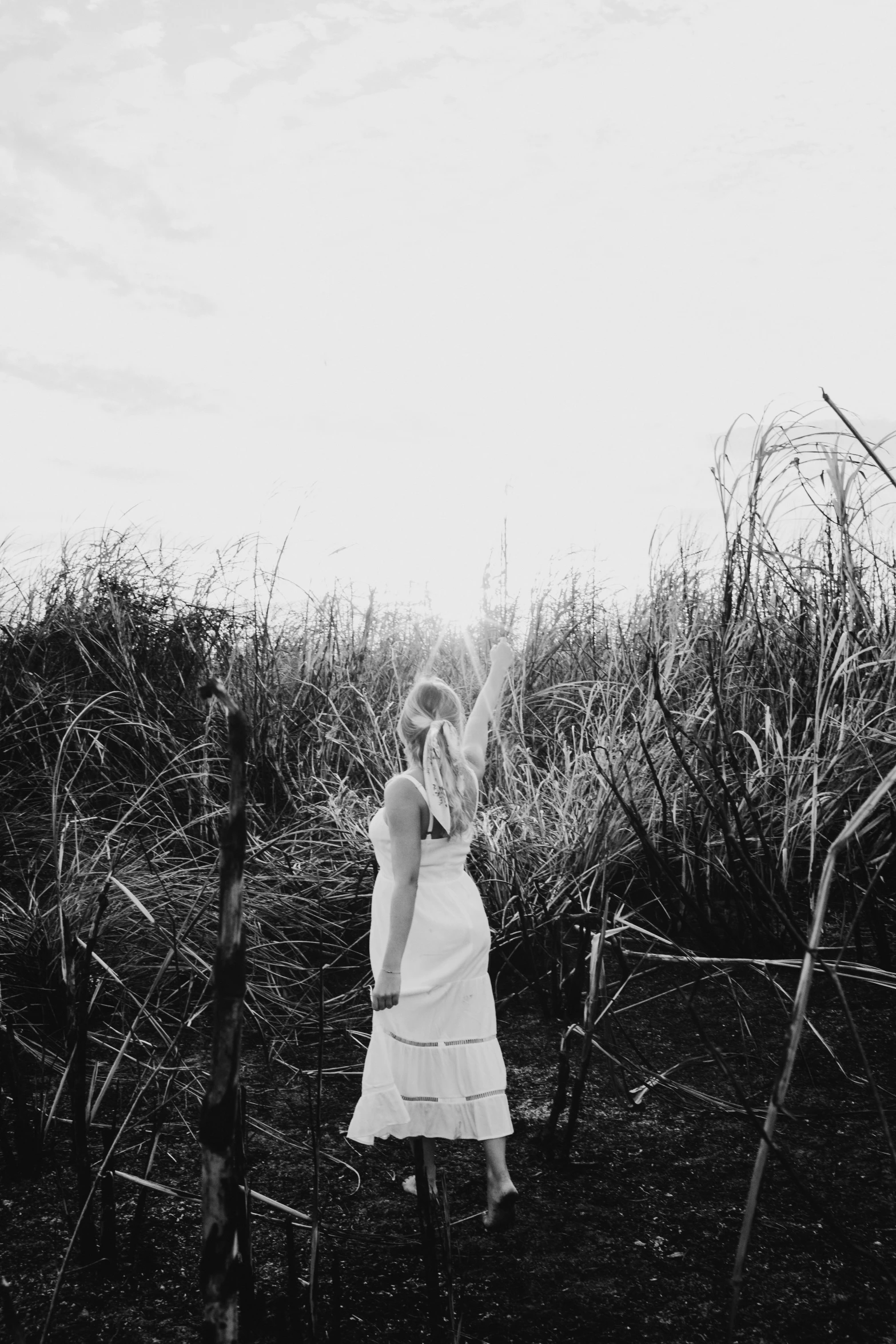 a woman is standing in a field and reaching for the frisbee