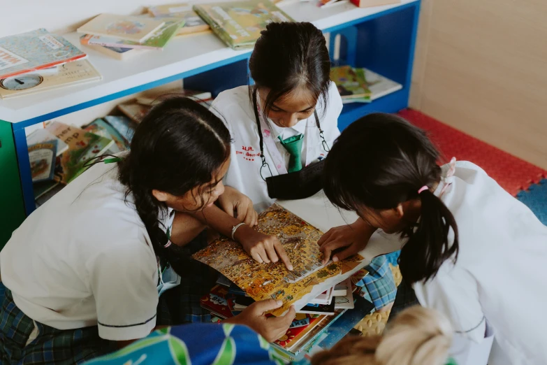 girls at school reading a book together