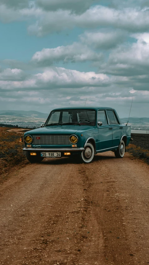 the old car is driving up a gravel road