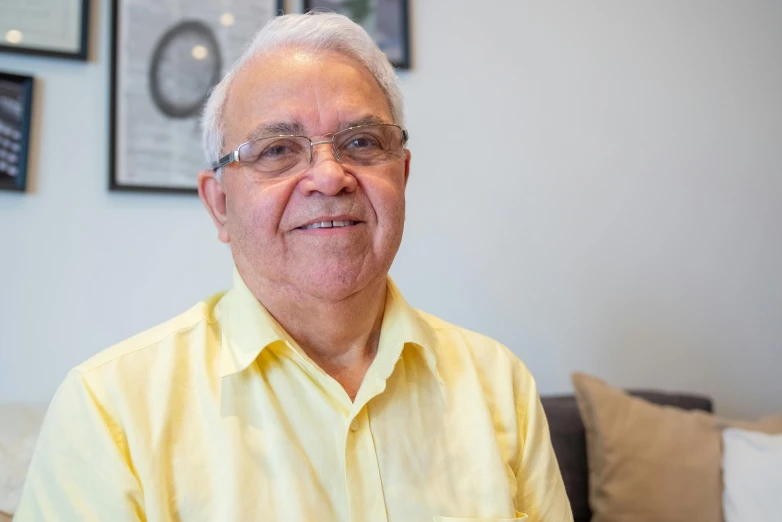 a older man with glasses and a yellow shirt in his home