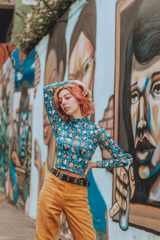 a woman standing in front of a wall painted with colorful art