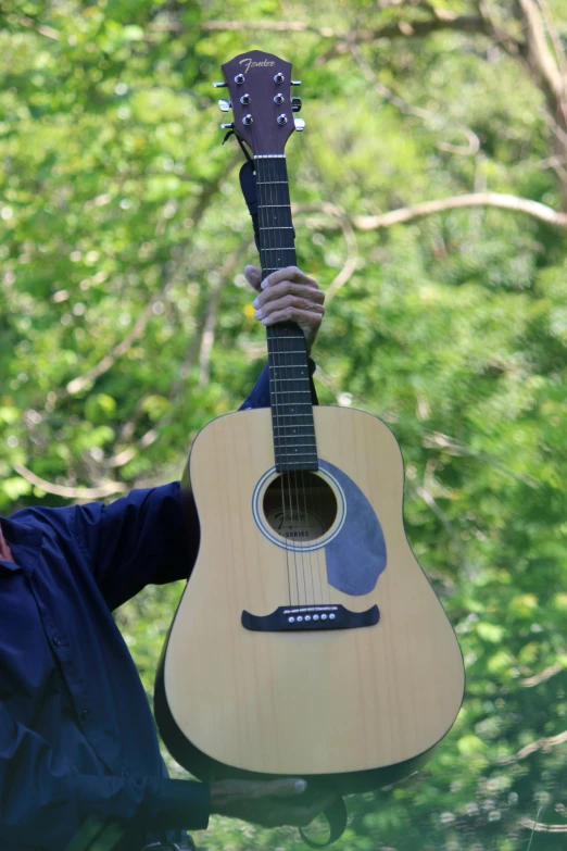 a man is holding a guitar in a forest