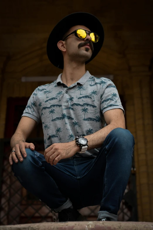 man sitting down wearing some sunglasses and a hat