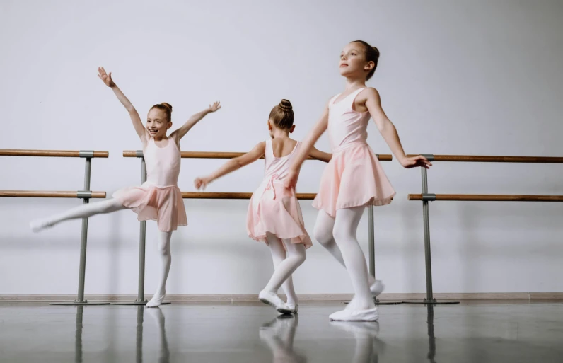 three girls in ballet pose and pose behind the bars