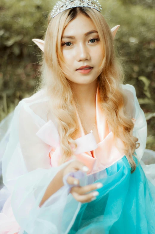 a girl in a fairy costume sitting in front of trees