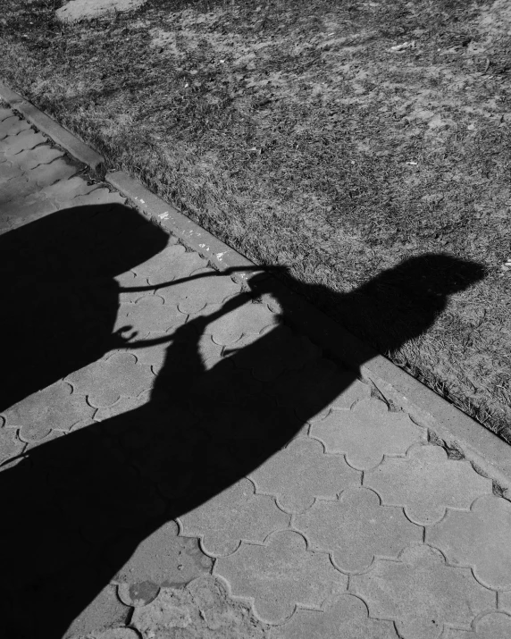 a person standing on the sidewalk with their shadow