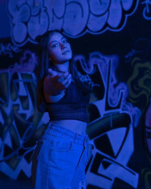 a girl with a black shirt and blue jean shorts pointing her finger