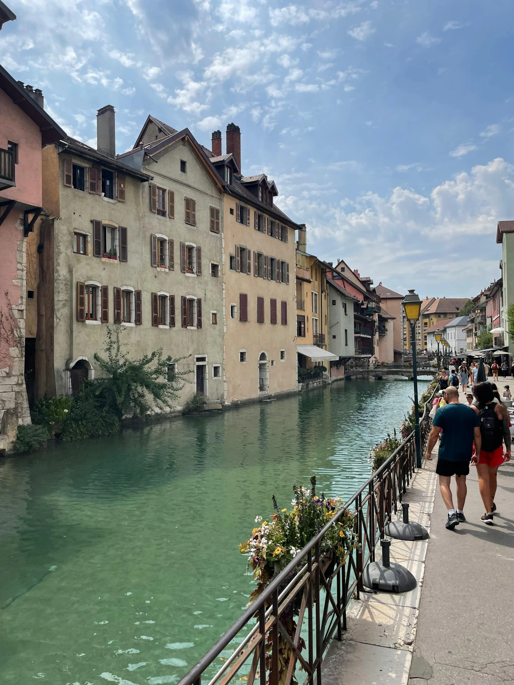 two people walk near a river while others look on