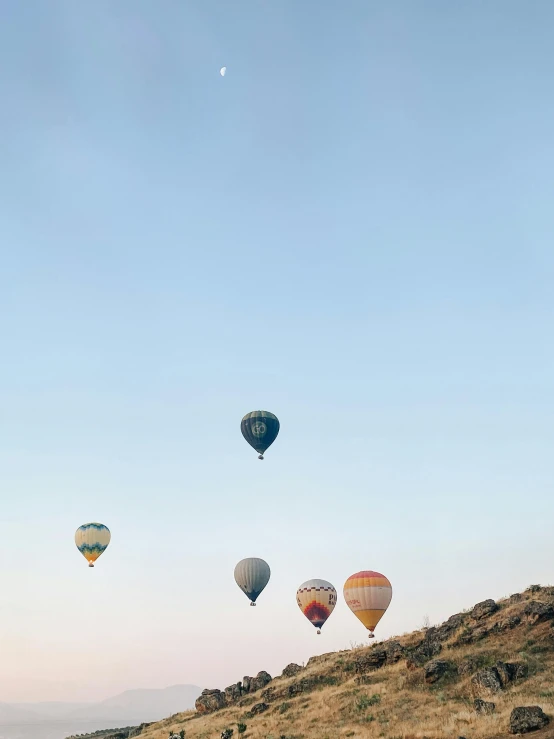 colorful balloons flying over grassy area next to mountain