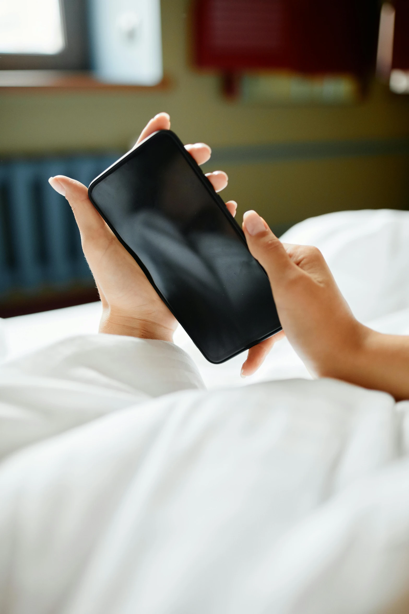 the hand holding a phone in bed