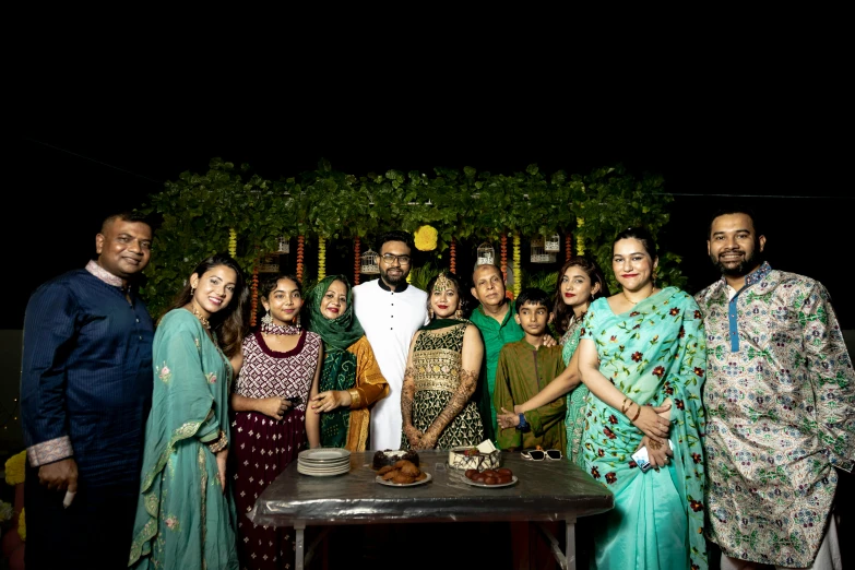 several people and a man standing in front of a cake