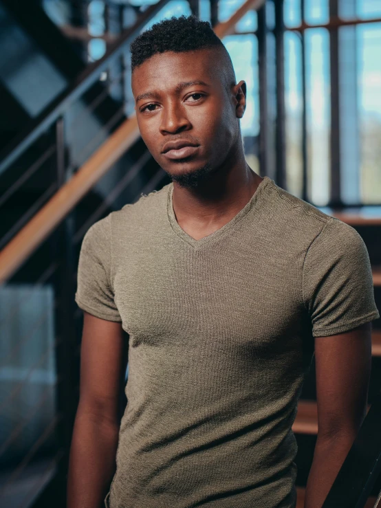 a man wearing a brown shirt stands in front of a staircase